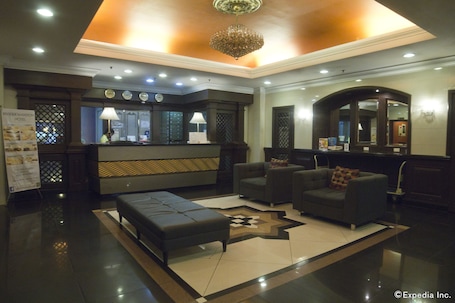 A lobby with a reception desk, seating area, and a large mirror.