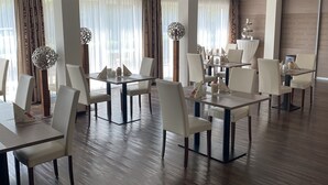 Un comedor moderno con suelo de madera, sillas blancas y mesas.