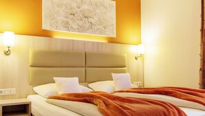 Habitación de hotel con una cama grande, dos lámparas de noche, un cabecero y una obra de arte colgada en la pared.