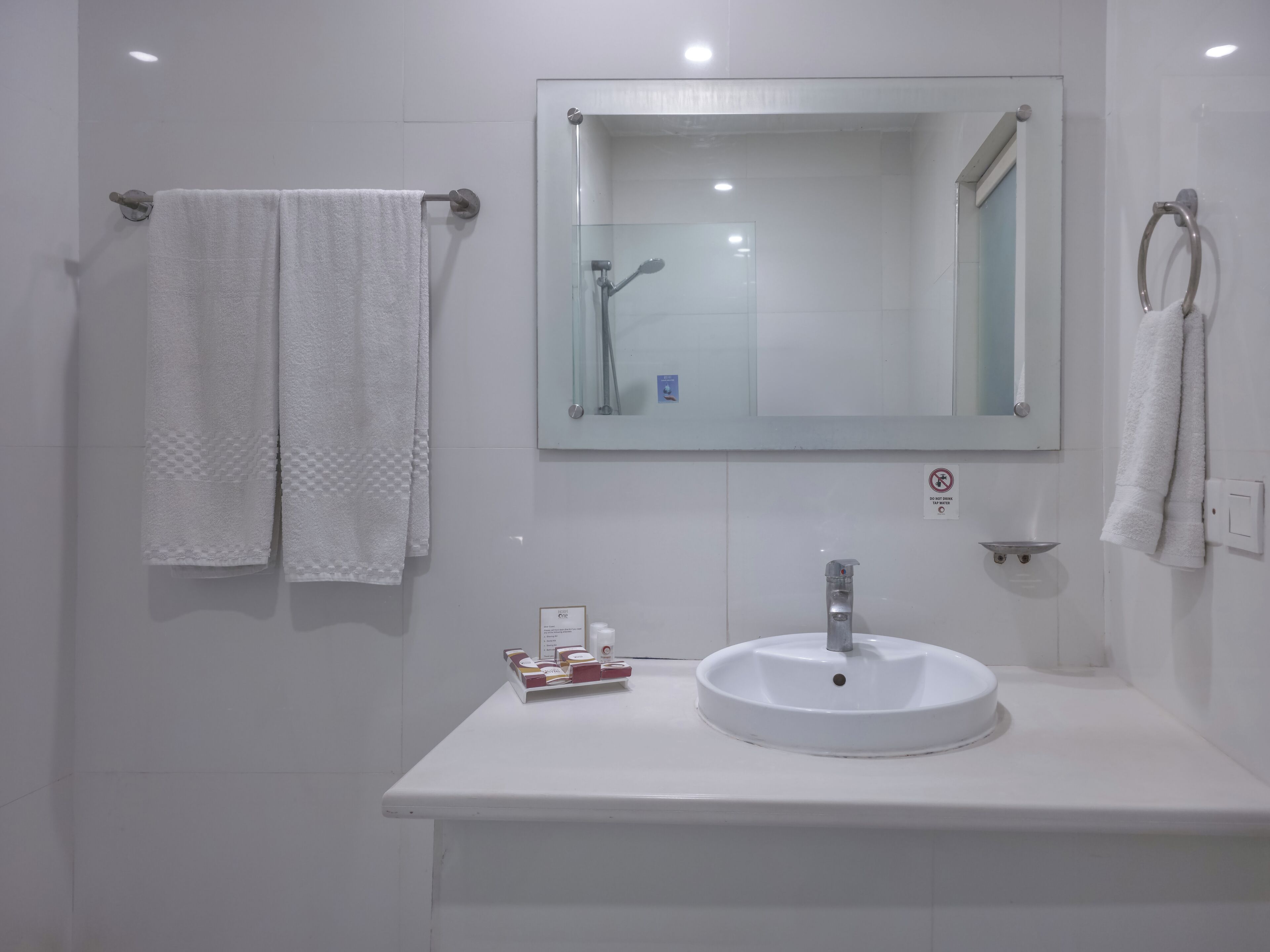 Ein Badezimmer mit einem weißen Waschbecken, einem Spiegel und zwei Handtüchern, die an Handtuchhaltern hängen.
