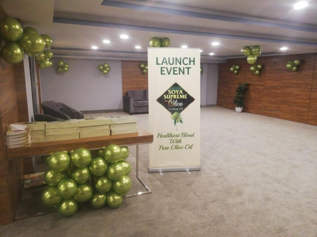A room with a reception desk, a banner for a launch event, and green spherical decorations.