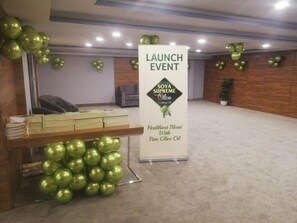Una stanza con una reception, uno striscione per un evento di lancio e decorazioni sferiche verdi.