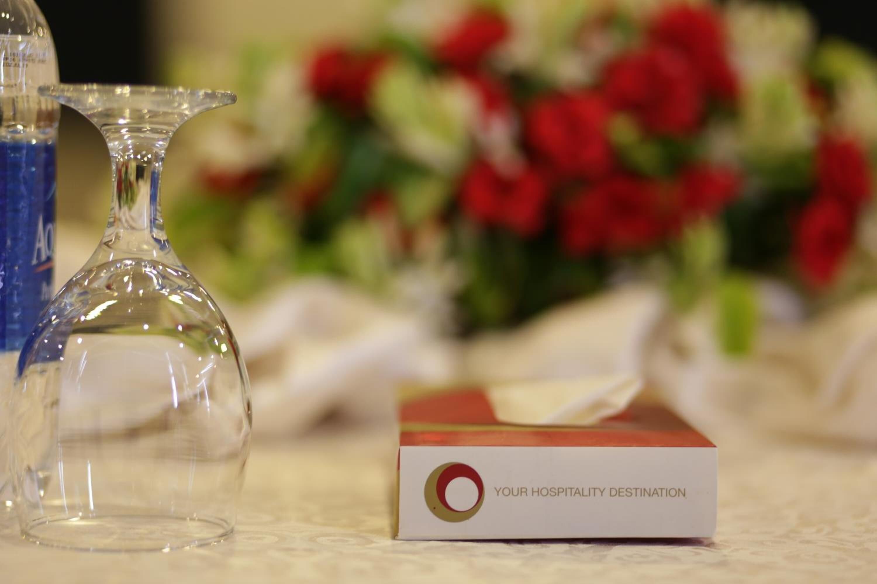 A clear glass vase and a box labeled "YOUR HOSPITALITY DESTINATION" on a table.