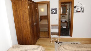 A bedroom with a wooden wardrobe, a bed, a small bathroom with a mirror and sink, and a wall-mounted cat decoration. - Nazhan Hotel - Boutique Class (Selçuk)