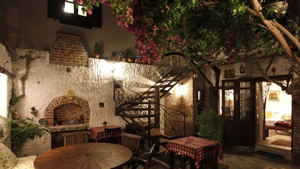 A rustic outdoor dining area with brick walls, a wooden staircase, and a brick oven. - Nazhan Hotel - Boutique Class (Selçuk)