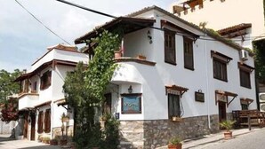A traditional white building with stone base, multiple windows, and potted plants. - Nazhan Hotel - Boutique Class (Selçuk)