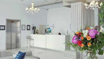 Un vestíbulo moderno con una recepción, área de descanso y un arreglo floral decorativo.