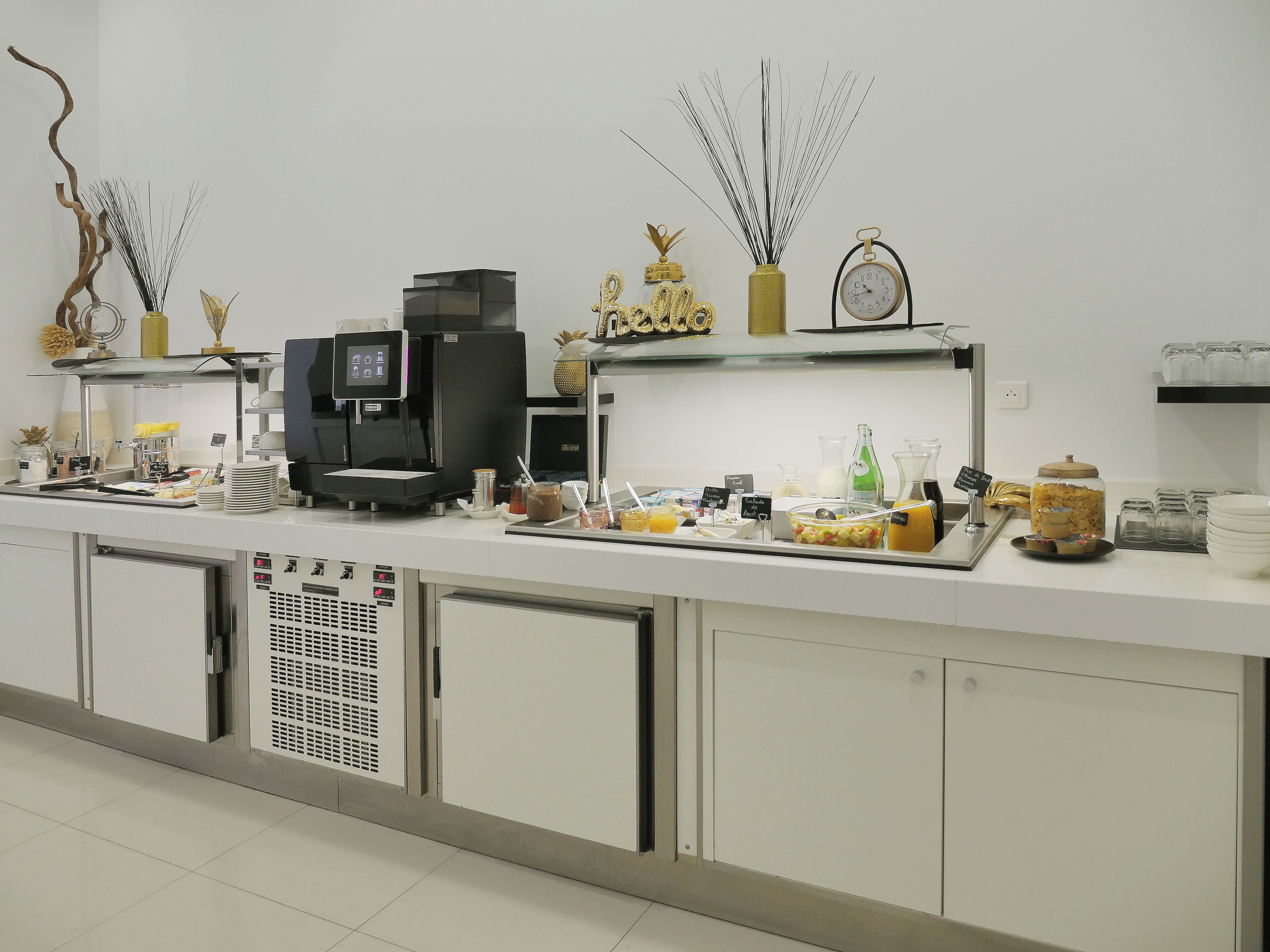 Een buffetopstelling met koffieautomaten, een klok en diverse bakken met eten en drinken.