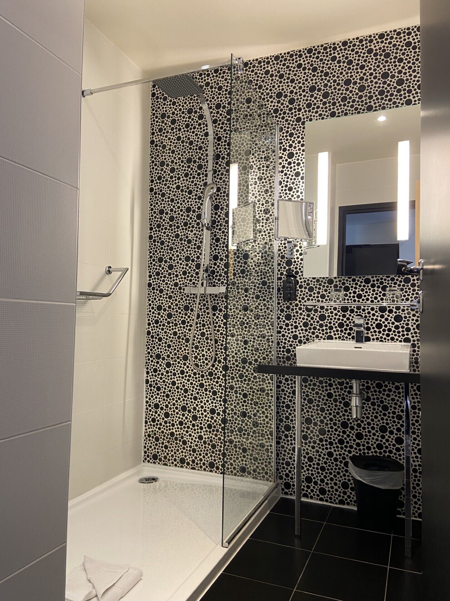 A modern bathroom with a glass-enclosed shower, a white sink, and a patterned wall.