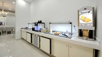 A modern kitchen area with a self-serve station, including a coffee machine and a juice dispenser.
