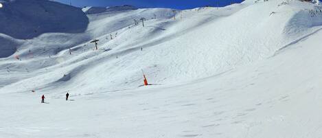 A snow-covered ski slope with ski lifts and skiers.