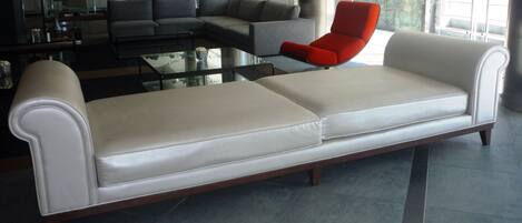 Una sala de estar moderna con un sofá blanco, un sillón rojo y un sofá modular gris.