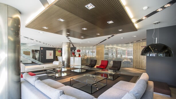 A modern lobby with a seating area, glass coffee tables, and a unique ceiling design.
