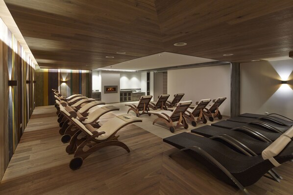 Una sala de conferencias moderna con filas de sillas y una larga mesa, suelo de madera e iluminación empotrada.