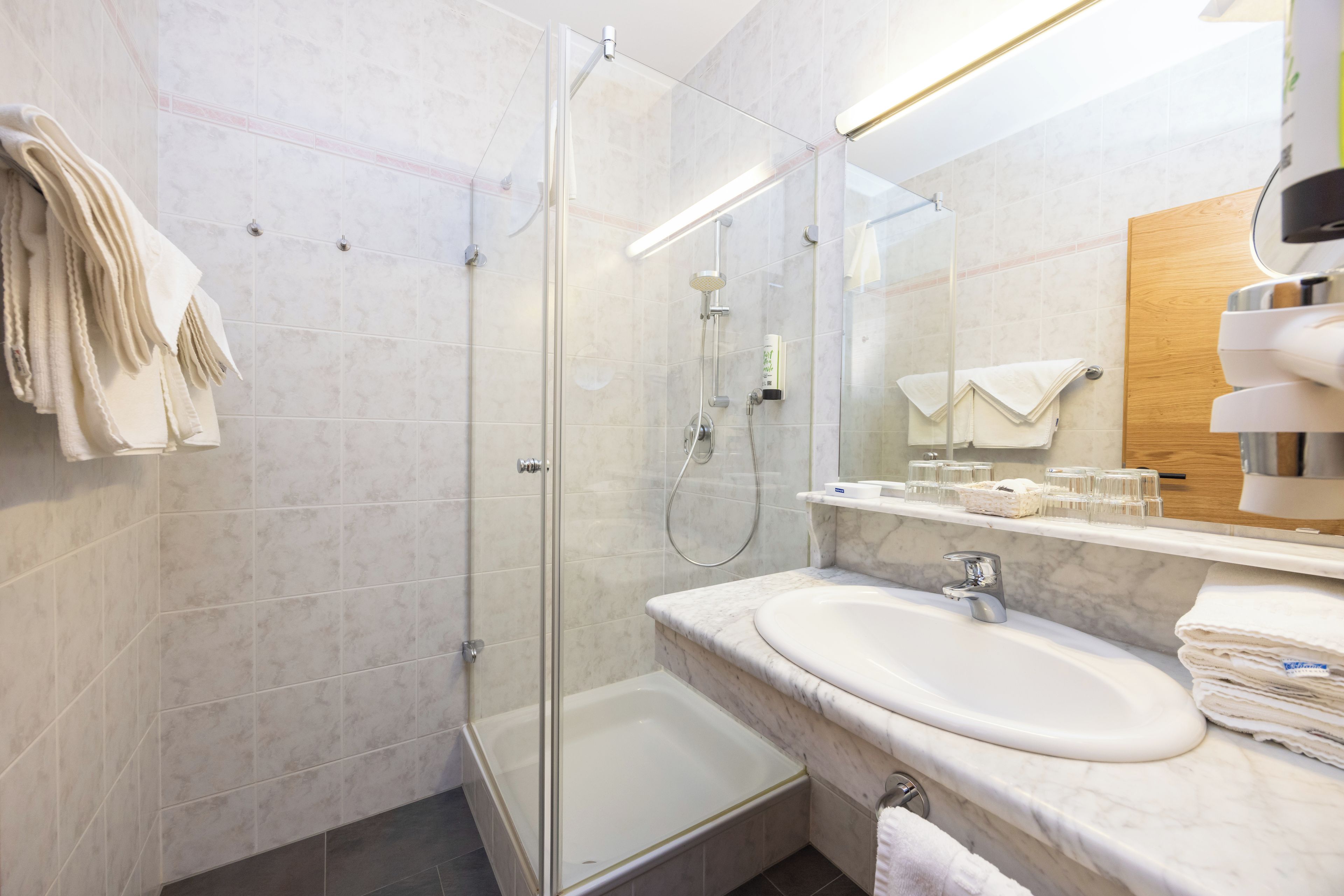 A modern bathroom with a glass-enclosed shower, a marble sink, and a large mirror.