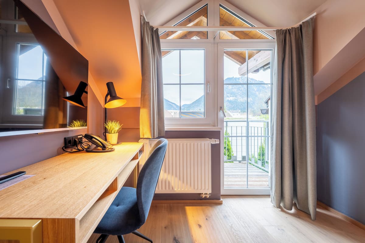 Ein modernes Zimmer mit einem Holztisch, einem Stuhl, einer Lampe und Bergblick durch große Fenster.
