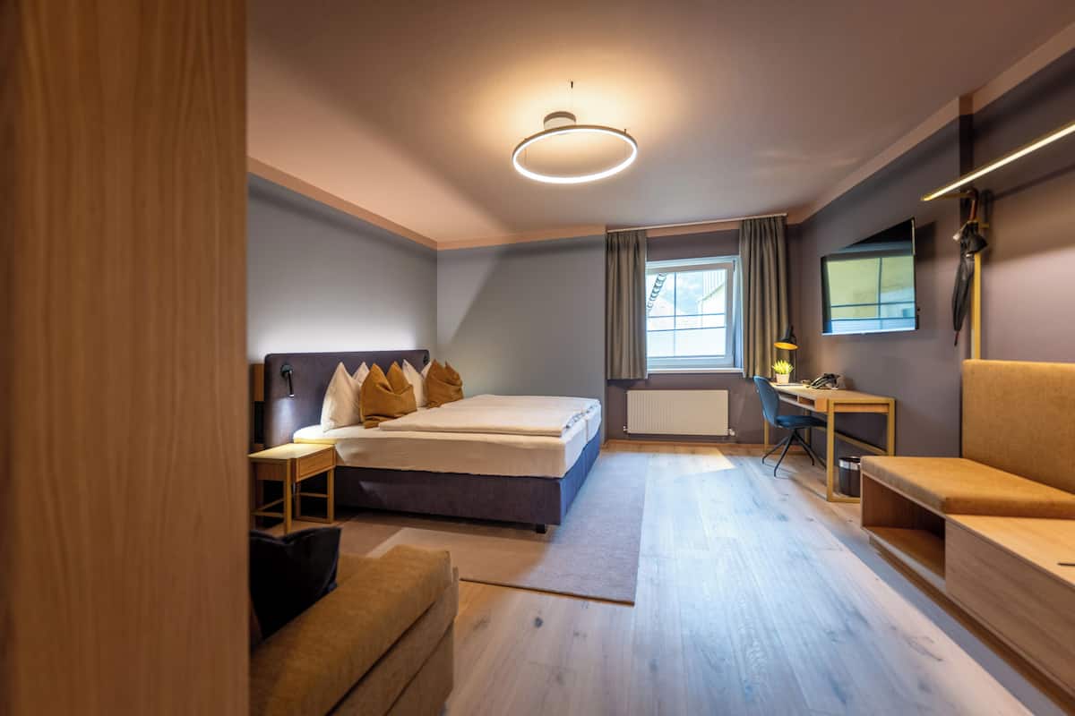 Ein modernes Hotelzimmer mit Bett, Schreibtisch, Stuhl und einer Couch.