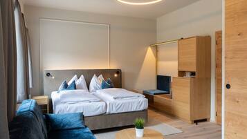 A modern bedroom with a bed, a sofa, a small table with a plant, and a wardrobe.