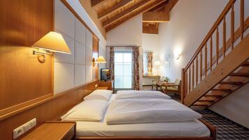 Ein Hotelzimmer mit einem hölzernen Bett, einem Schreibtisch, einem Stuhl, einem kleinen Tisch und einer Treppe.