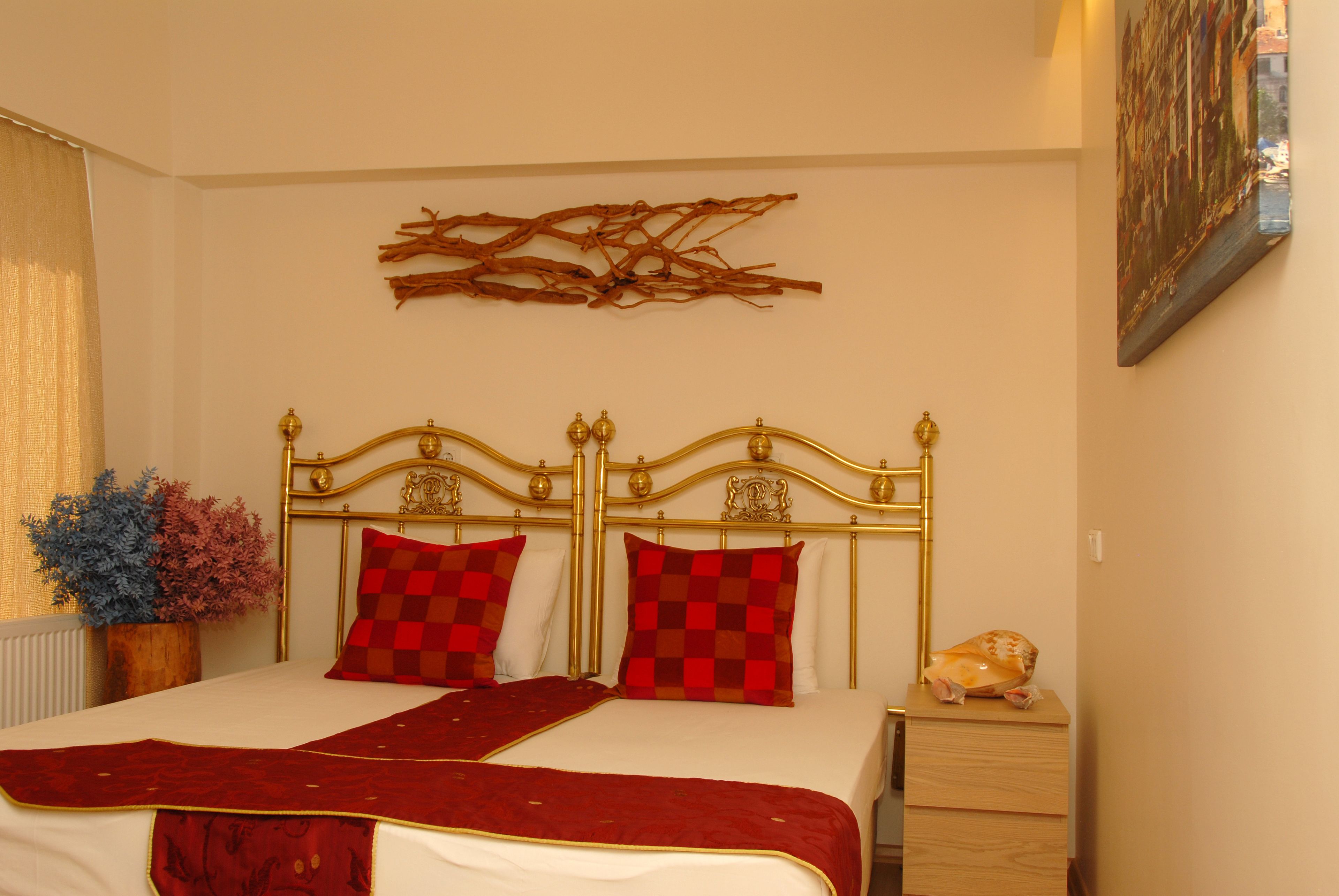 Ein Schlafzimmer mit einem großen Bett, einem Holz-Nachttisch, einer dekorativen Zweig-Wanddekoration und einem Bild an der Wand.
