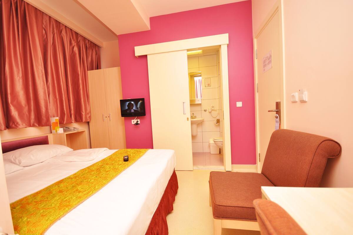 A hotel room with a bed, a television, a bathroom, and a seating area.
