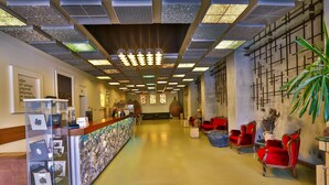 A hotel lobby with a reception desk, framed pictures, red chairs, and a decorative wall. - Han Hotel (Istanbul)