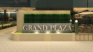 Une enseigne pour l’hôtel Grand Plaza CV Resort, avec un parterre de verdure en arrière-plan.