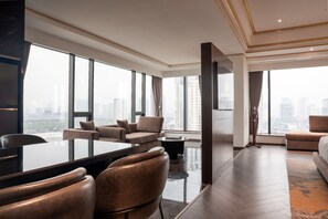 A modern hotel room with a large window, a sofa, a dining table, and a TV. - Grand Plaza Hotel Hanoi  (Hanoi)