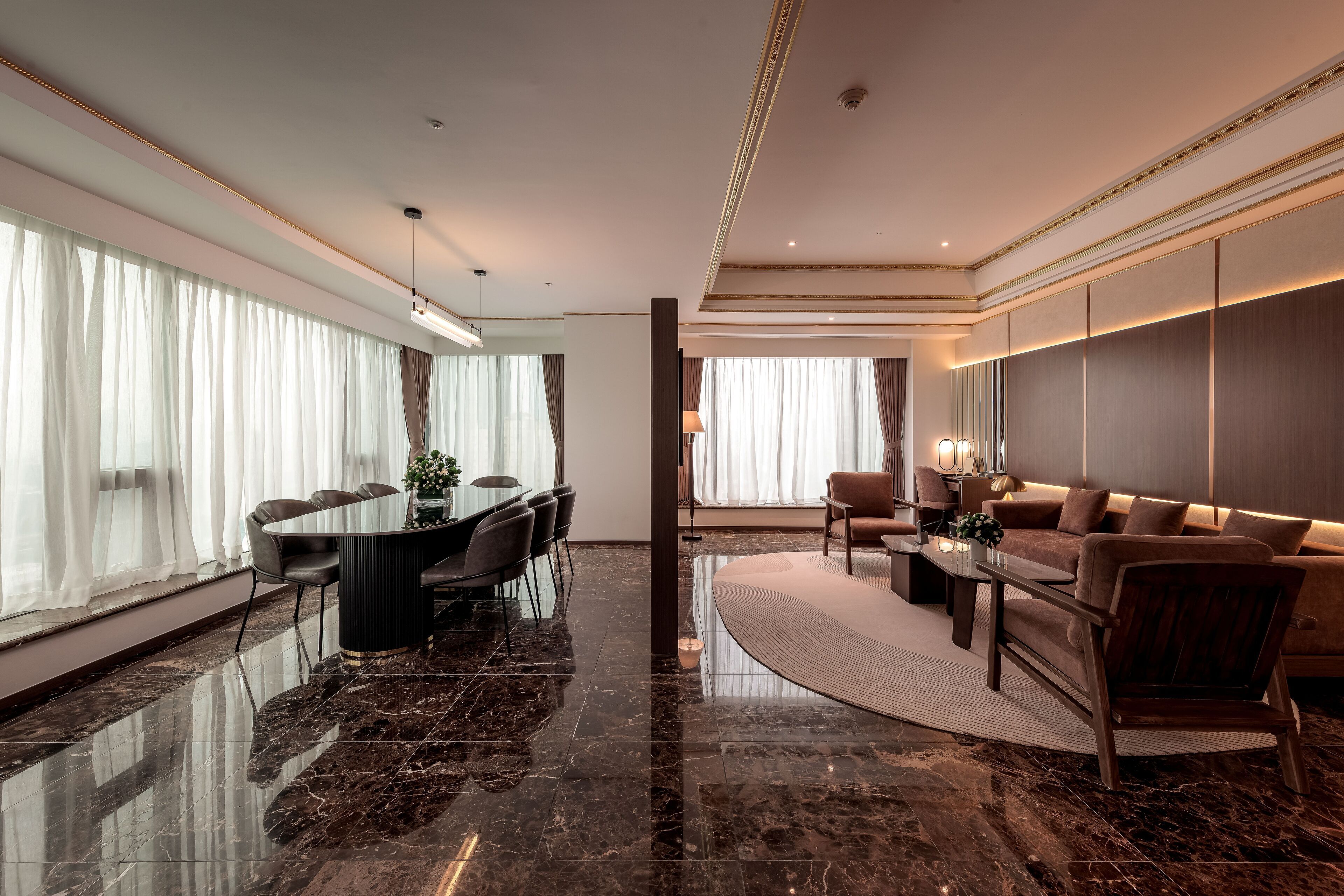 A spacious living area with a marble floor, a dining table with chairs, a sofa, and a coffee table.