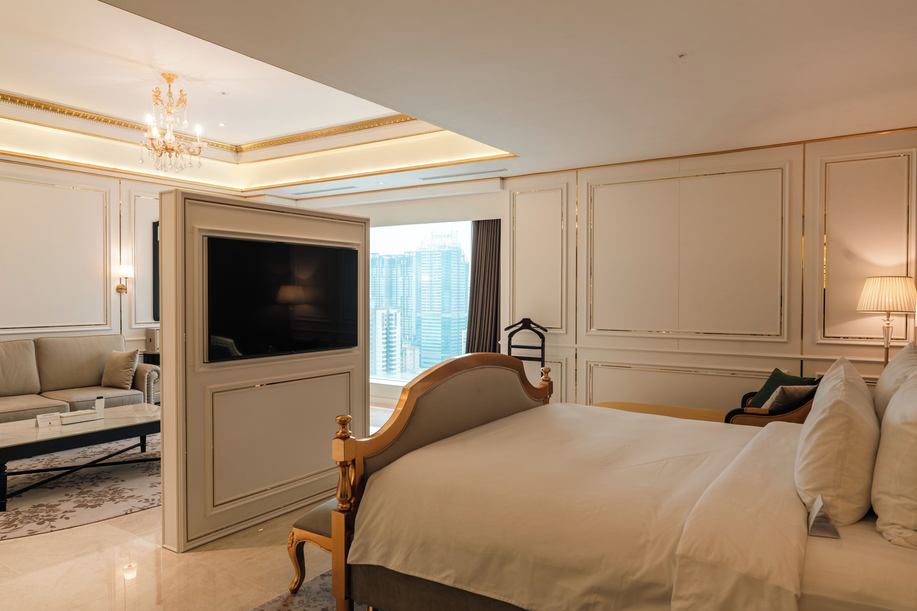 Habitación de hotel con una cama grande, televisión, sofá y vistas a la ciudad.
