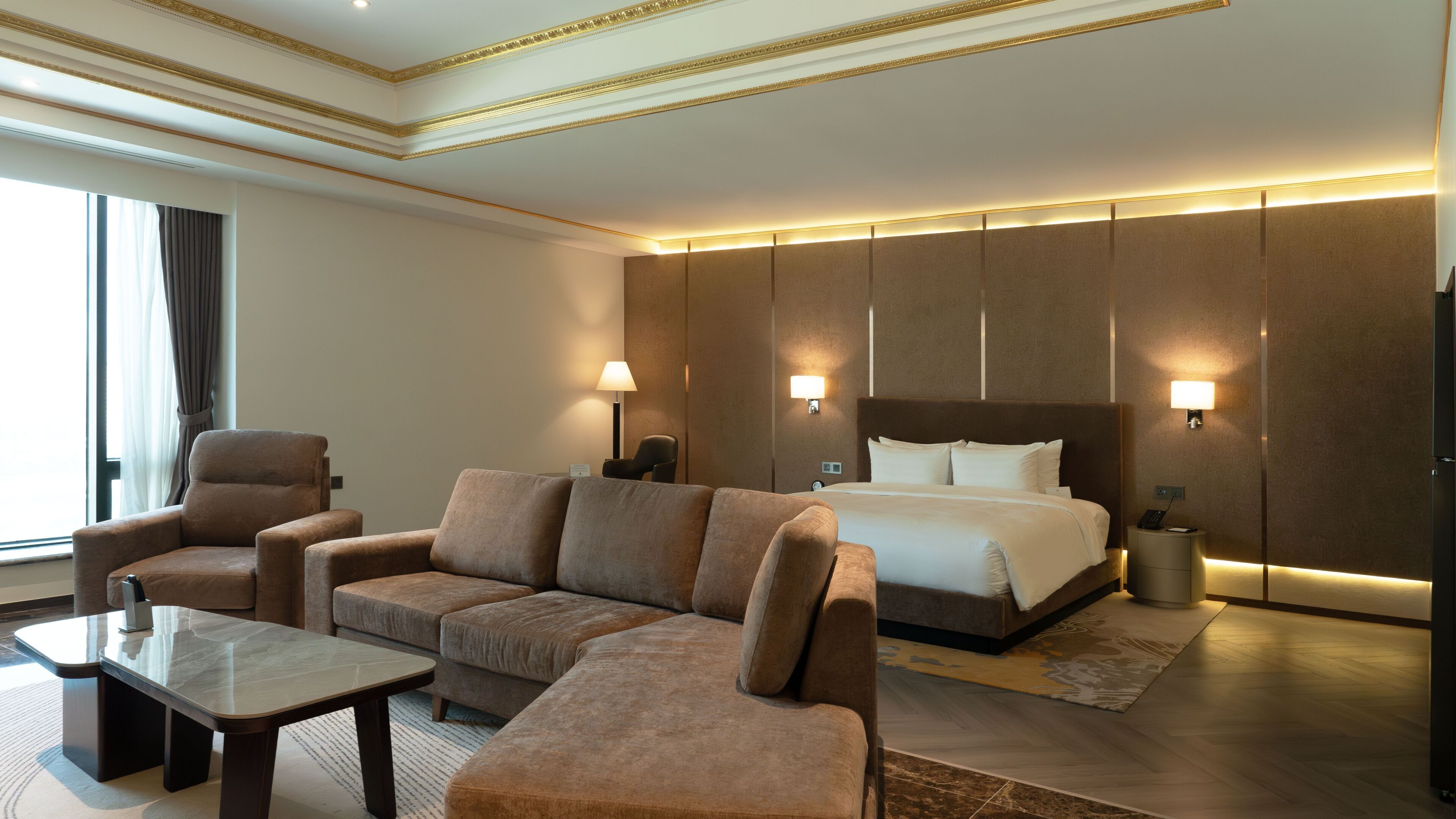 Una habitación de hotel con una cama grande, dos sillones, un sofá, una mesita y lámparas de pared.