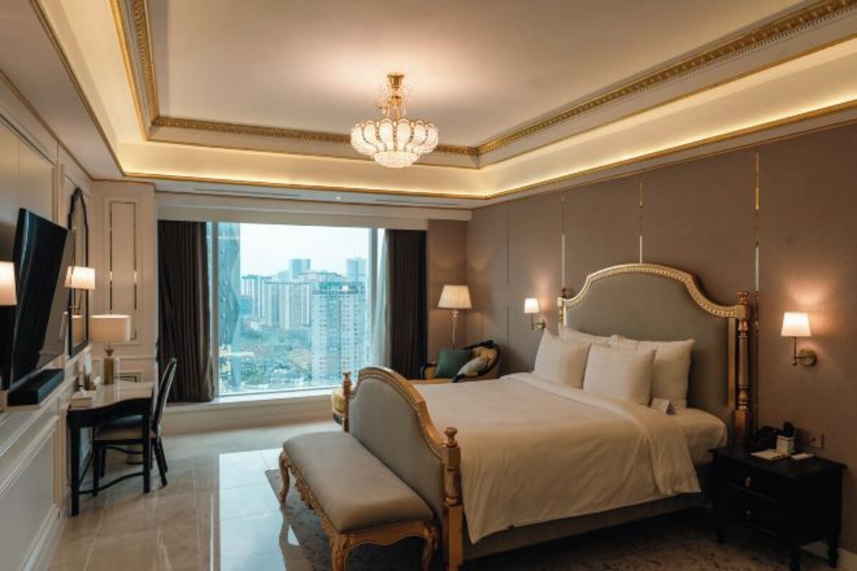 Une chambre d’hôtel avec un grand lit, des lampes de chevet, un bureau et une vue sur la ville.