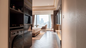 Une chambre d’hôtel moderne dotée d’un grand lit, d’une télévision, d’une armoire et offrant une vue sur le paysage urbain.
