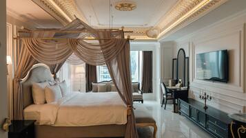 A luxurious bedroom with a four-poster bed, a large mirror, a television, and a desk with a lamp.