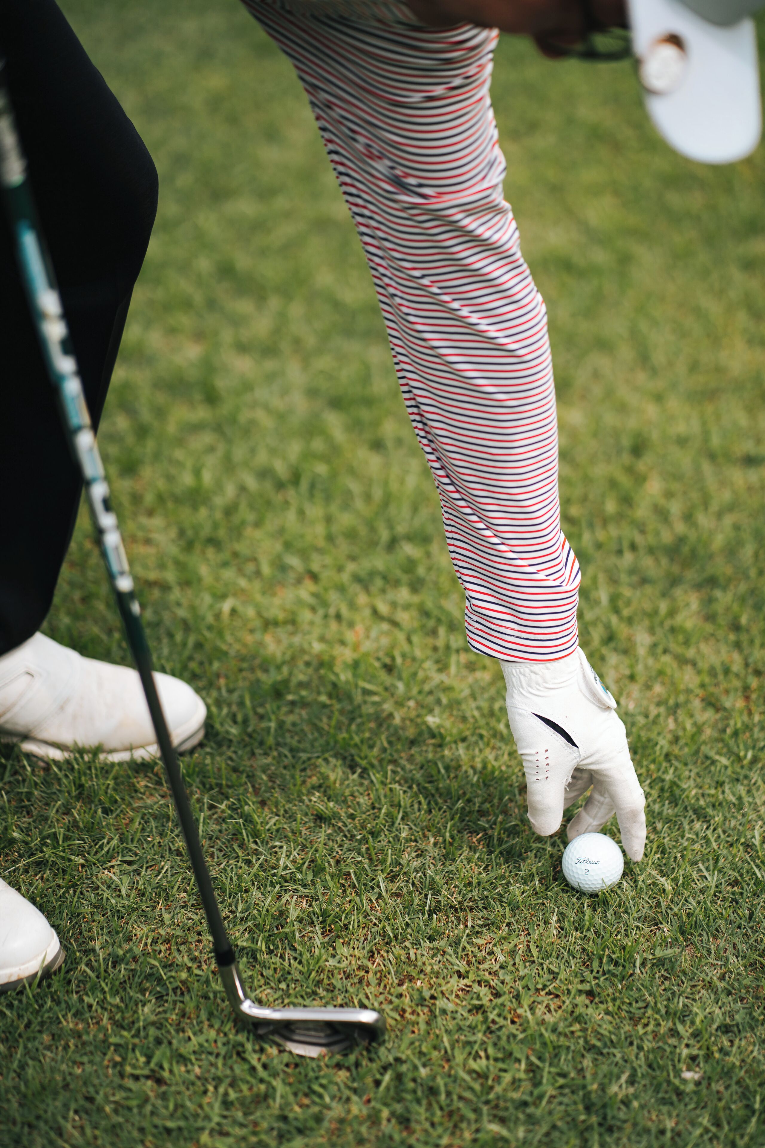Een close-up van een golfclub en een golfbal op een gazon.