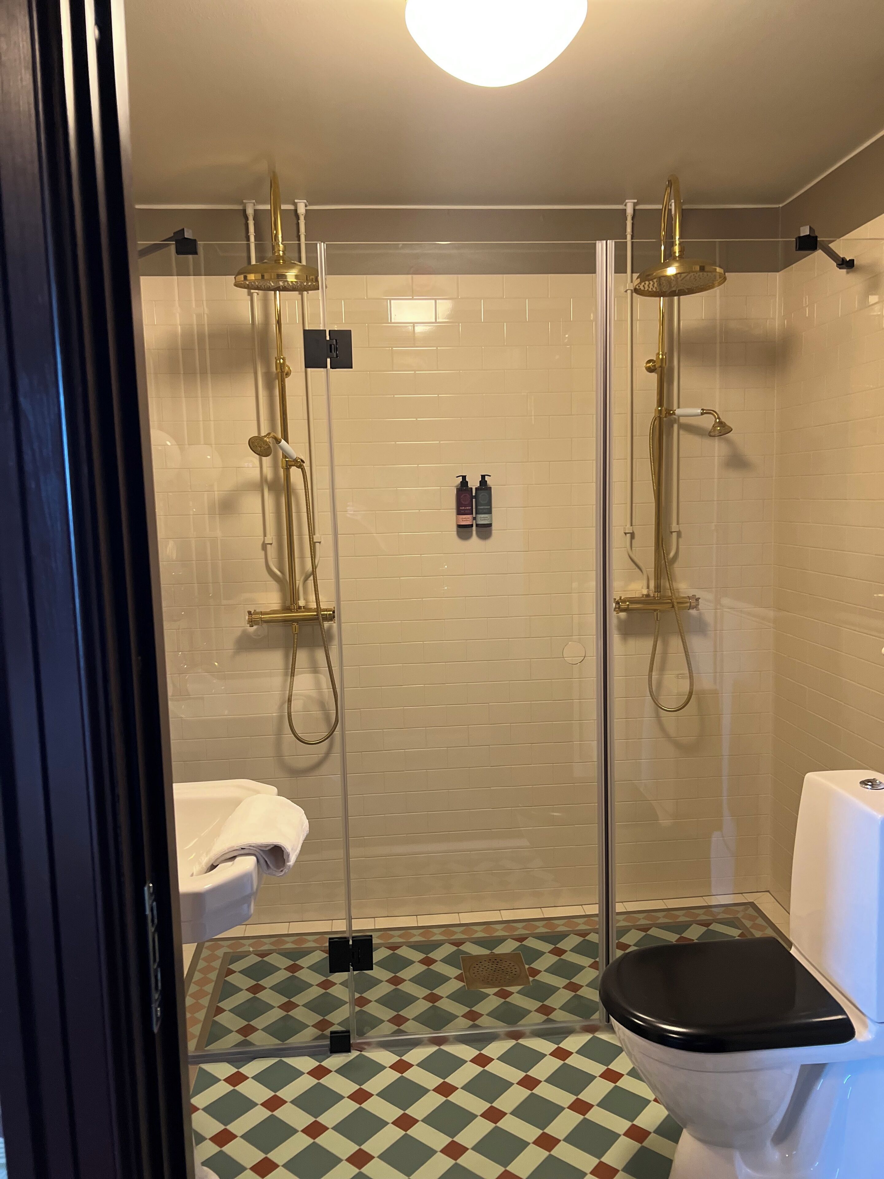 A bathroom with a shower, toilet, and a tiled floor.