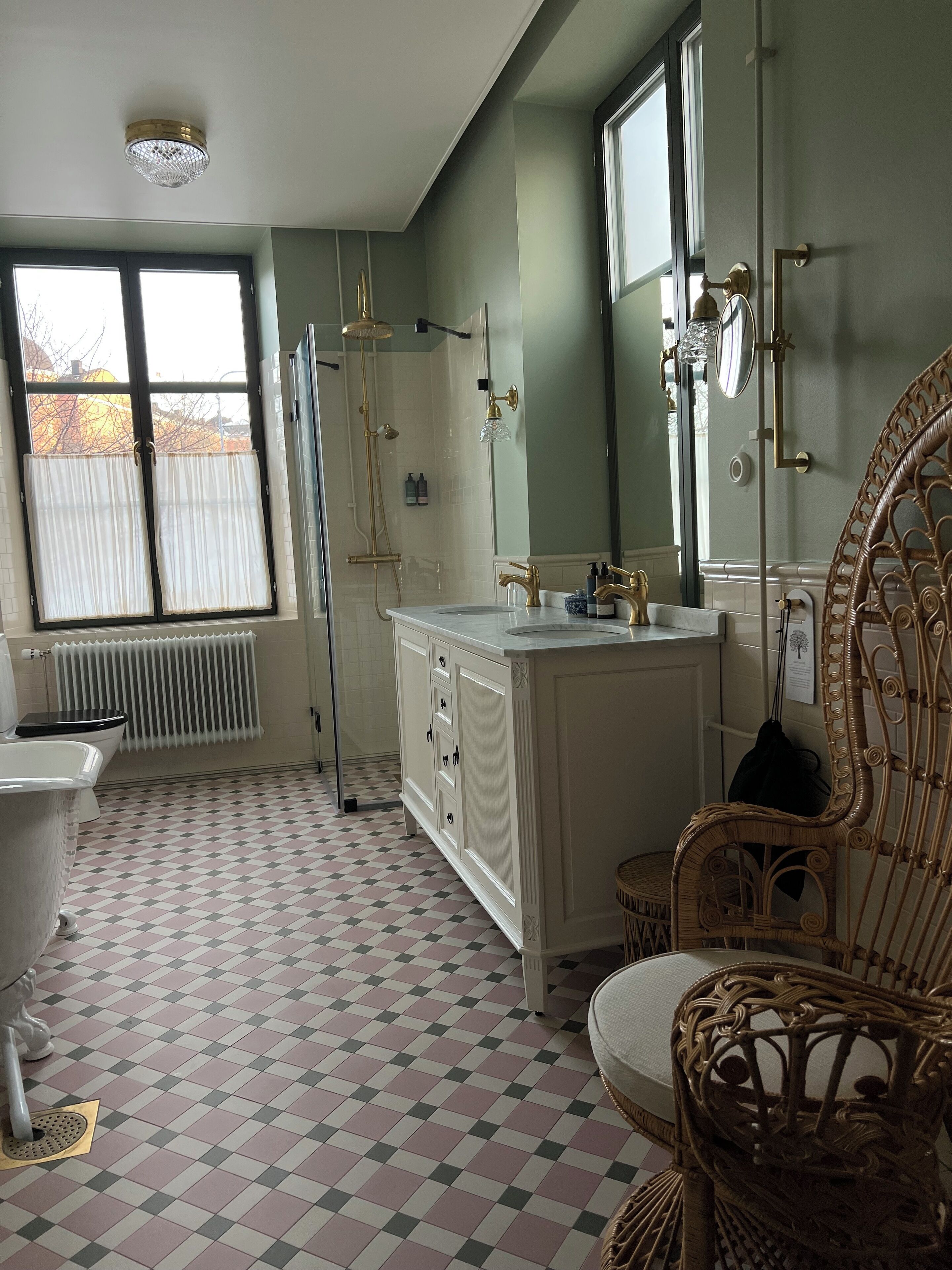 Ein Badezimmer mit Schachbrettboden, einem weißen Waschbecken, einem Spiegel und einer Dusche mit Glastür.