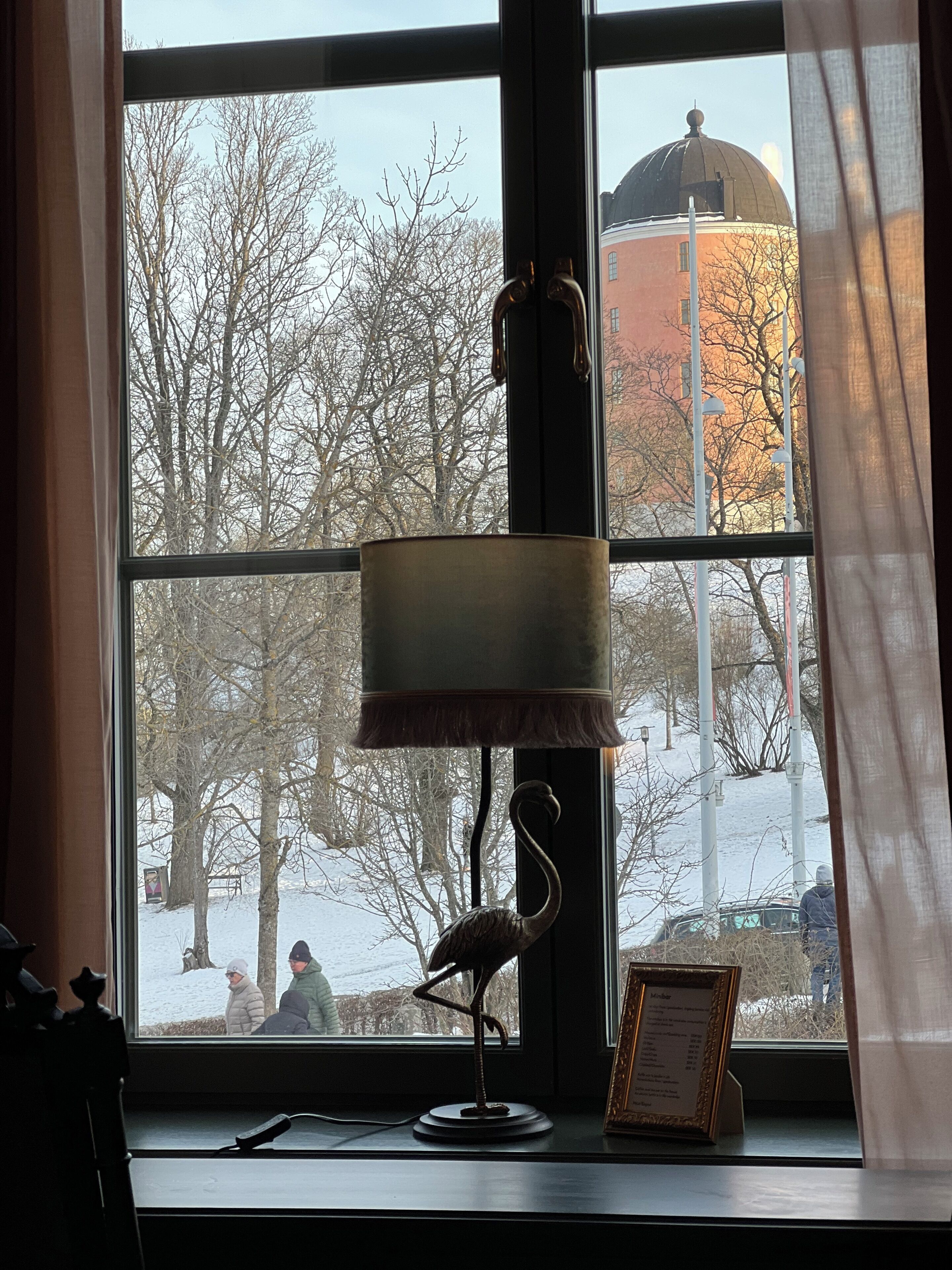 A room with a large window, a lamp, and a framed picture on the windowsill.