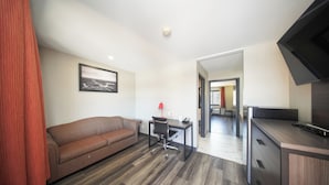 Een moderne kamer met een bank, bureau en kitchenette.