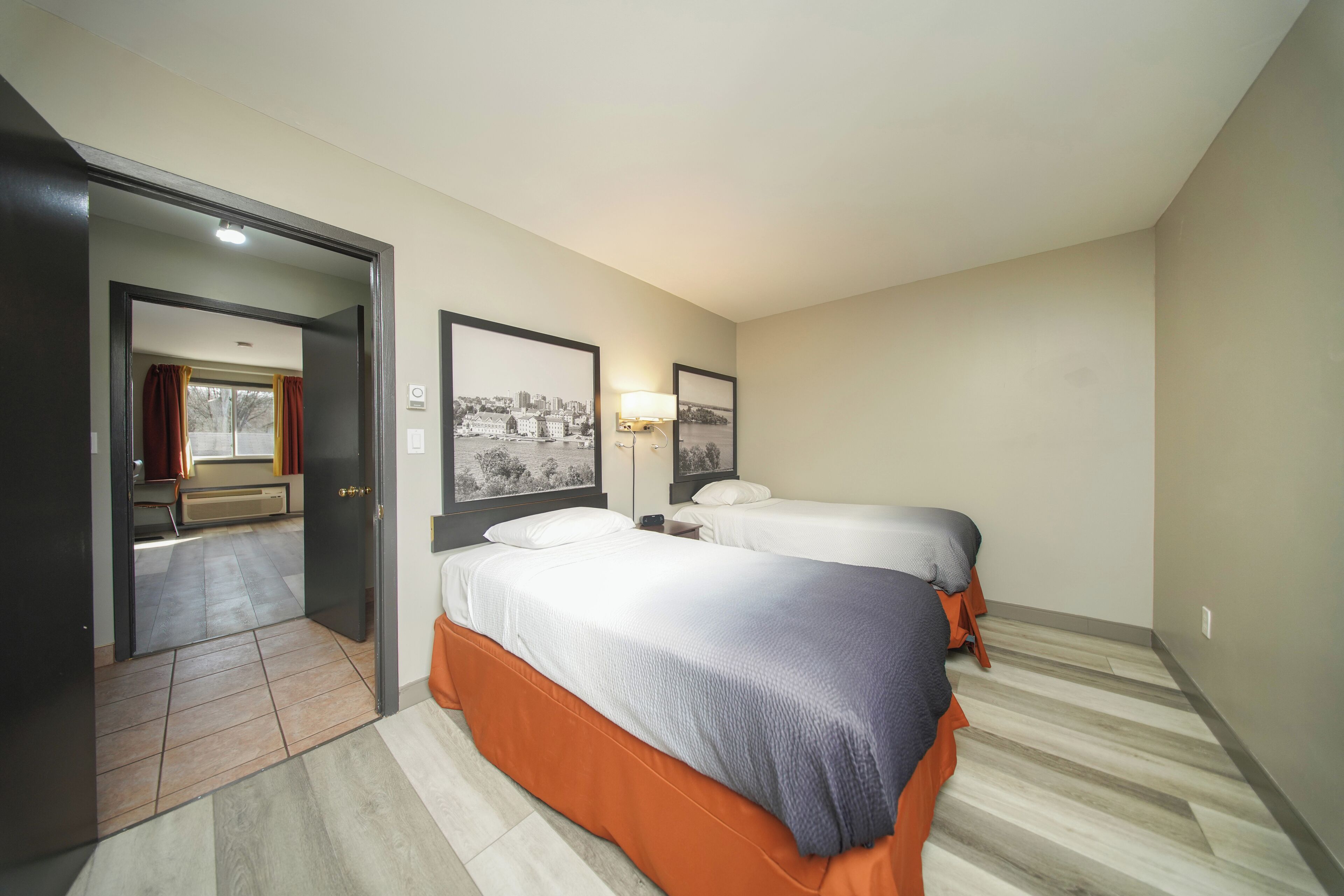 Une chambre d’hôtel avec deux lits, une vue sur la ville et une porte donnant accès à la salle de bain.