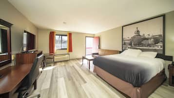 A hotel room with a bed, desk, chair, and a large window.