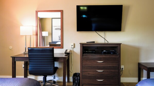 Habitación de hotel con escritorio, silla, televisión y cómoda.