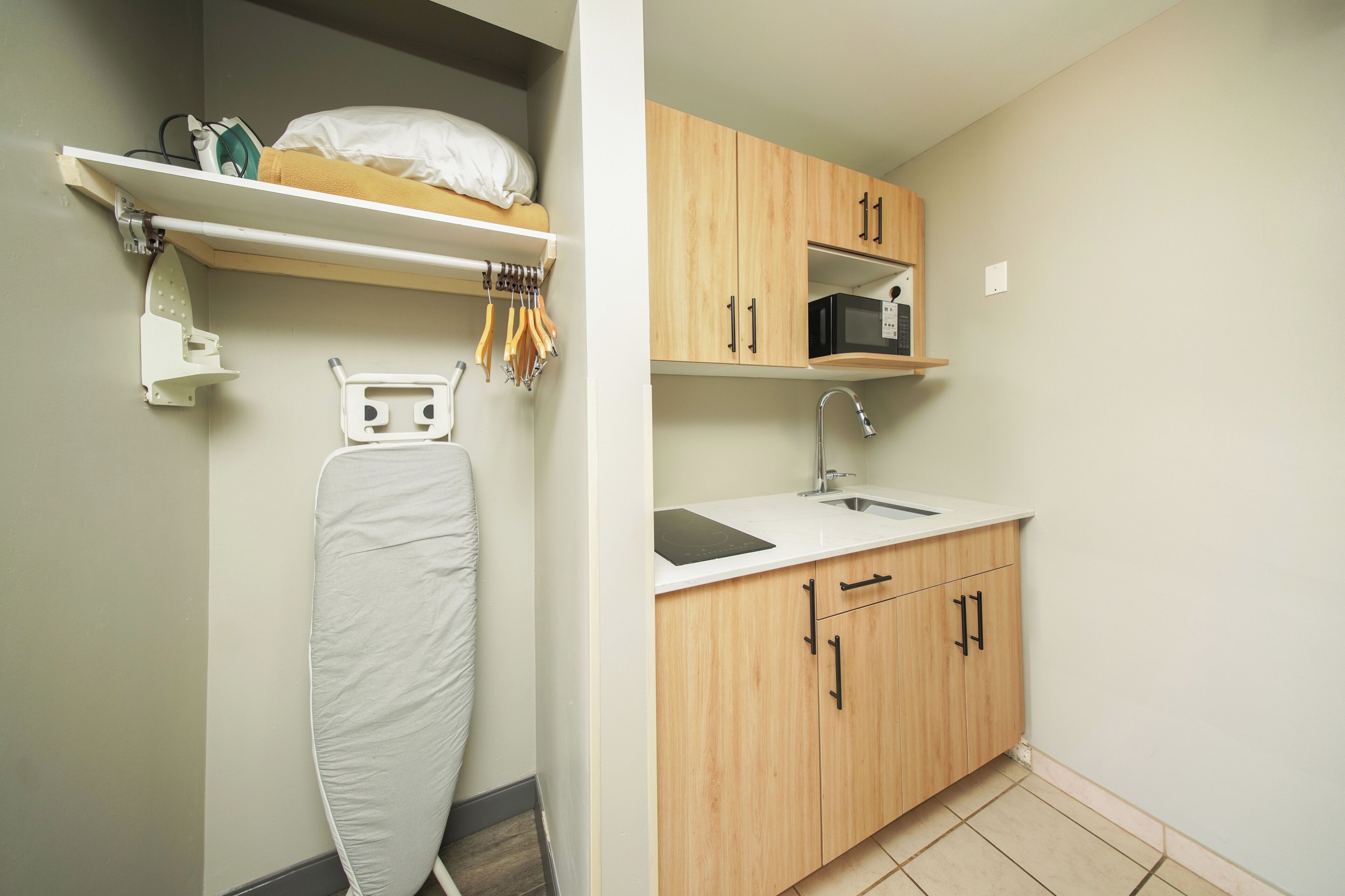 Una cocina compacta con armarios de madera, un microondas y una plancha integrada.