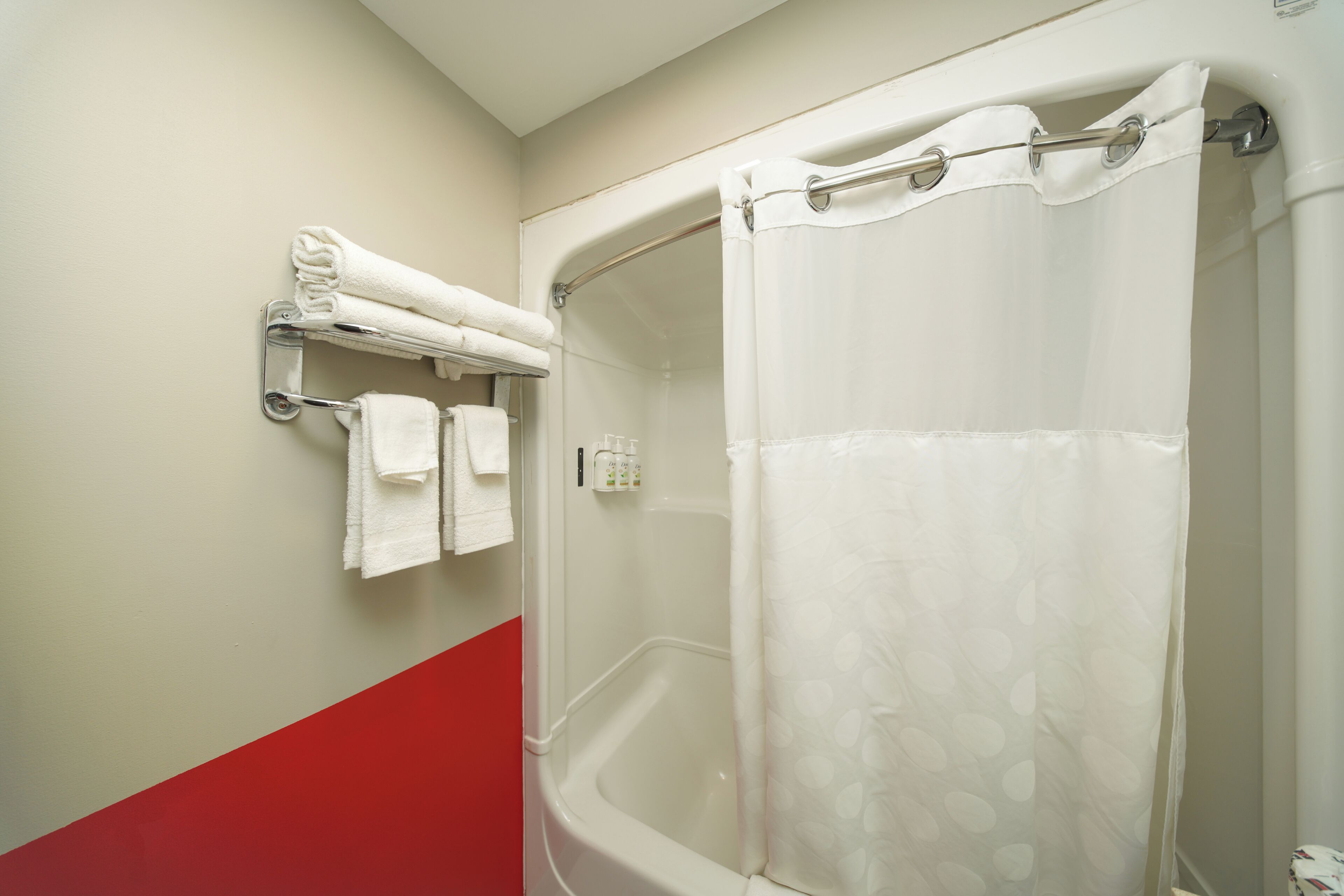 Ein Badezimmer mit einer weißen Badewanne, einer Duschvorhangs und einem Handtuchhalter mit gefalteten Handtüchern.