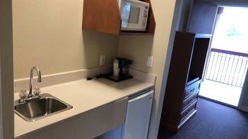 Cocina compacta con un lavamanos integrado, un microondas y un refrigerador pequeño.