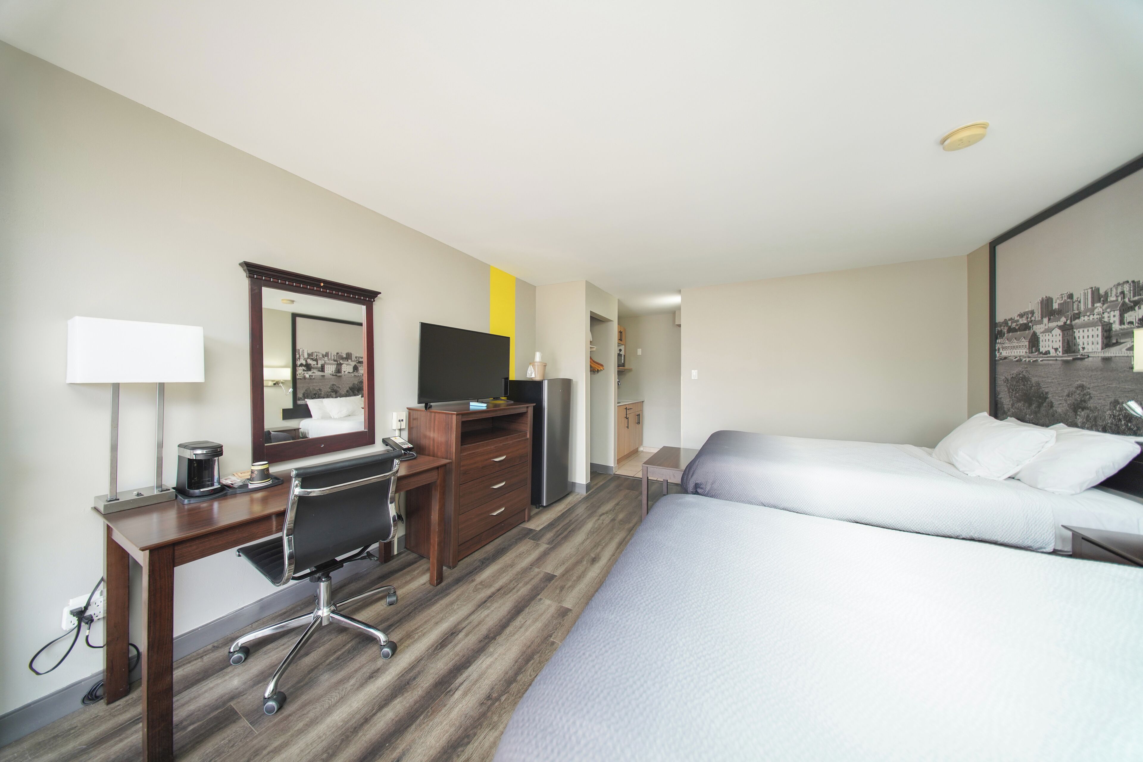 Hotelkamer met een bureau, twee bedden, een spiegel en uitzicht over de stad.