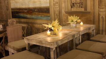 A dining area with a rustic wooden table, cushioned stools, and a mural of a landscape.