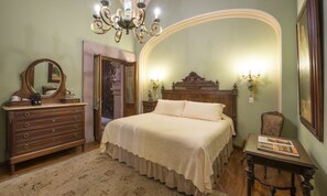 A bedroom with a wooden bed, a dresser, a mirror, and a chandelier. - Hotel Museo Palacio de San Agustin (San Luis Potosi)