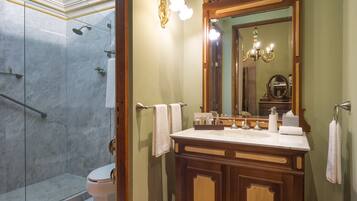 Une salle de bain avec une douche à parois de verre, un meuble-lavabo en bois doté d’un grand miroir et des toilettes blanches.