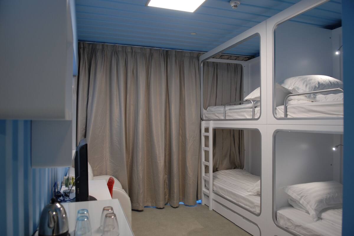 A bunk bed room with a desk, curtains, and a ceiling light.